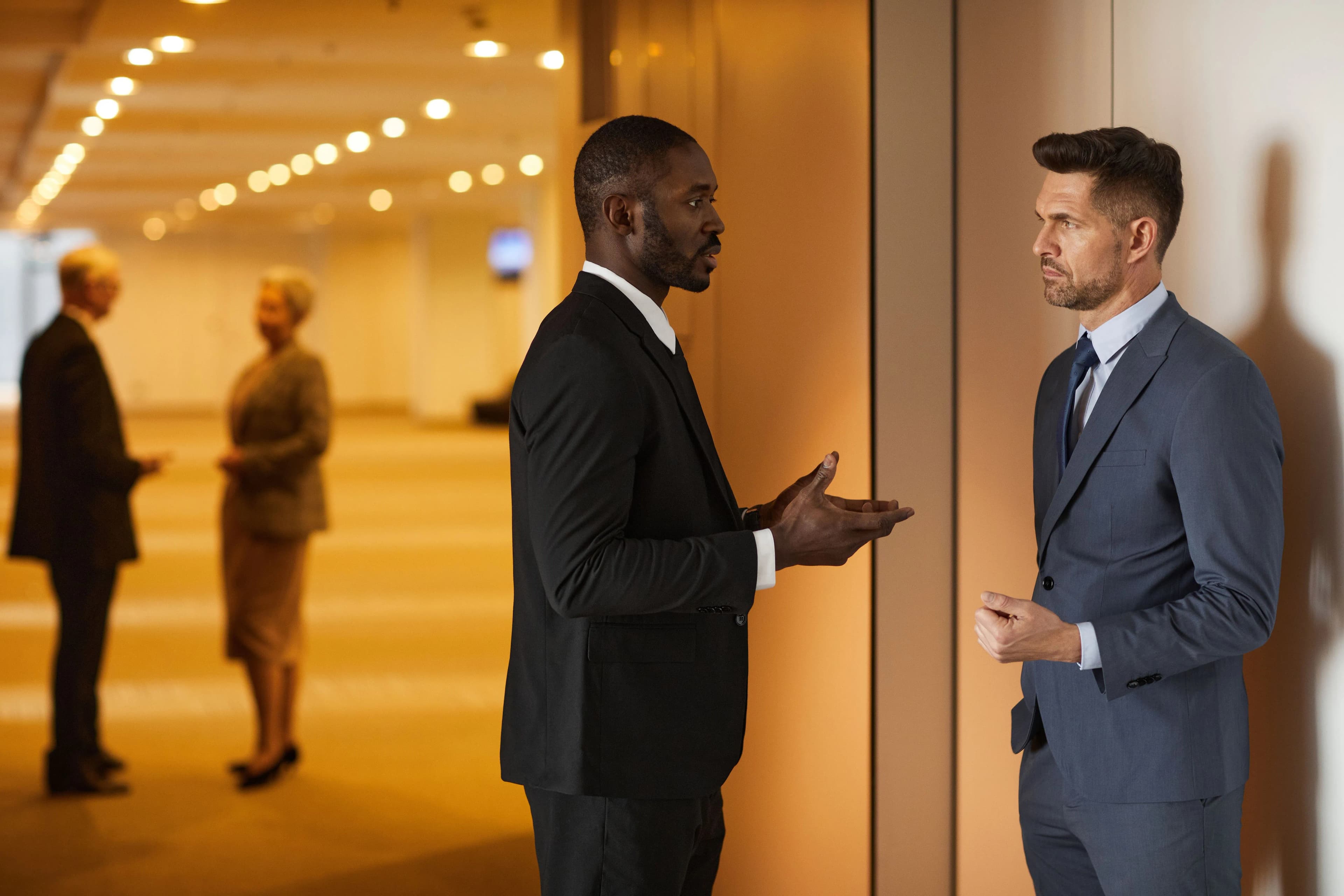 Two people in business attire talking inside an event venue